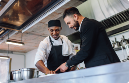 Two men discussing food in a kitchen