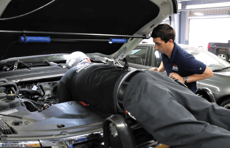 Two men working on the engine of a vehicle.